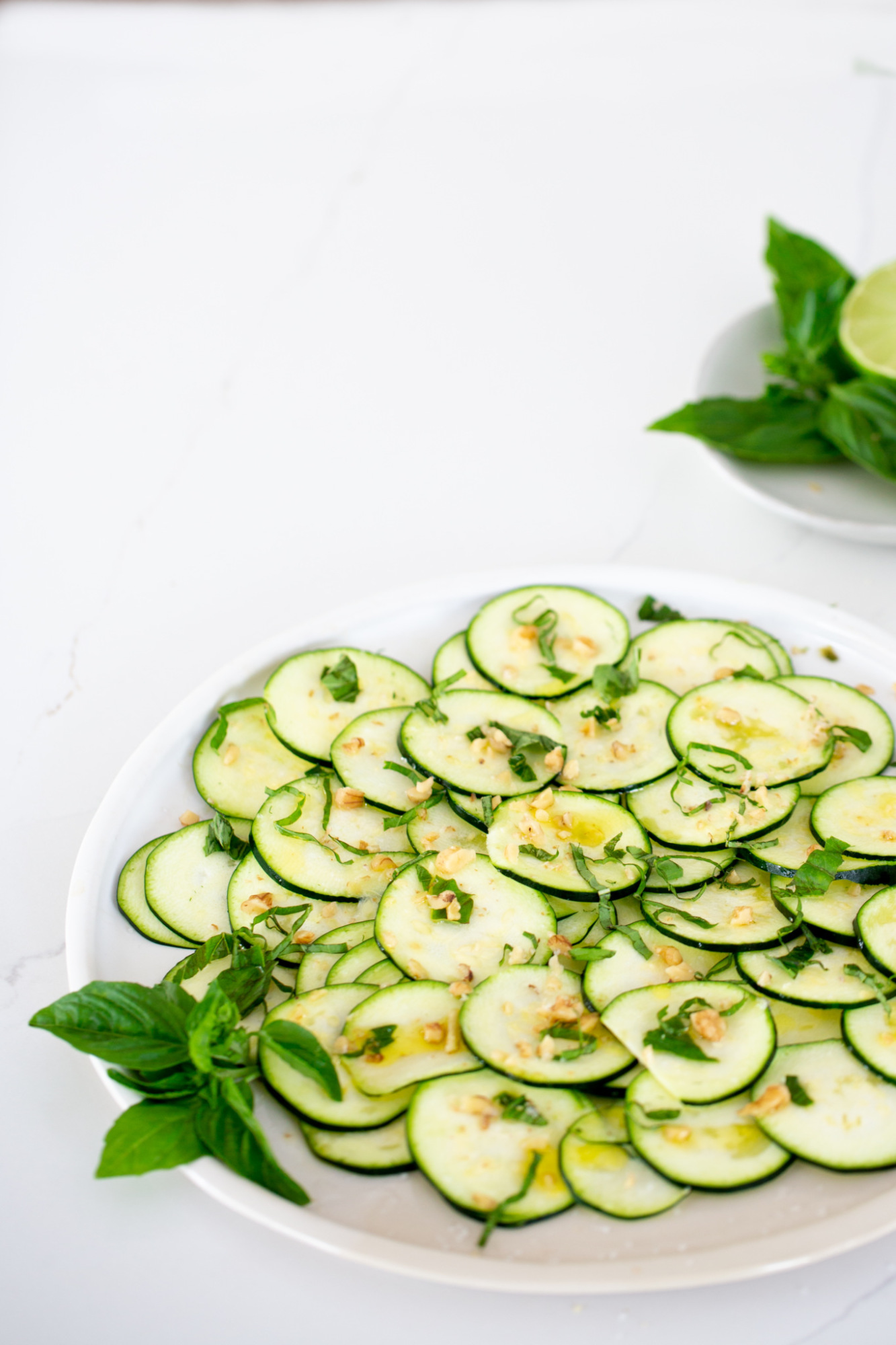 Carpaccio de calabacín en un platón blanco y con hojas de albahaca