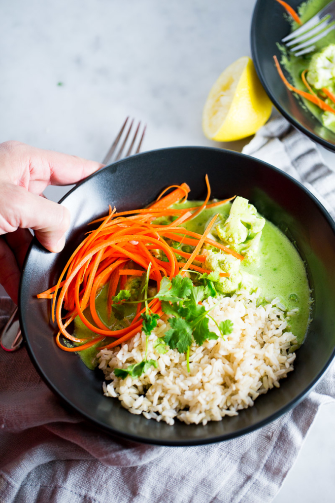 Cury verde thai hecho en casa servido sobre arroz integral y verduras
