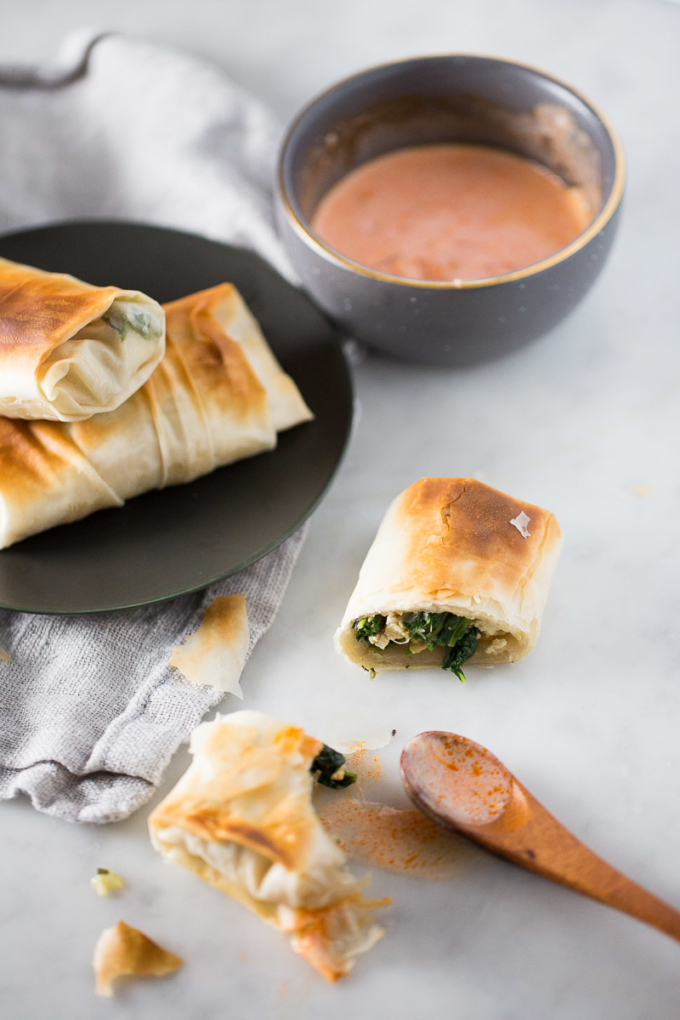 rollos de Spanakopita,vegana sobre y plato y con salsa rosa a un lado