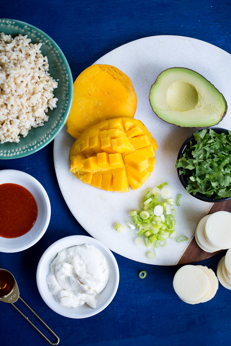 Mango aguacae, scallions, cilantro y palmitos en tabla para picar y fondo azul