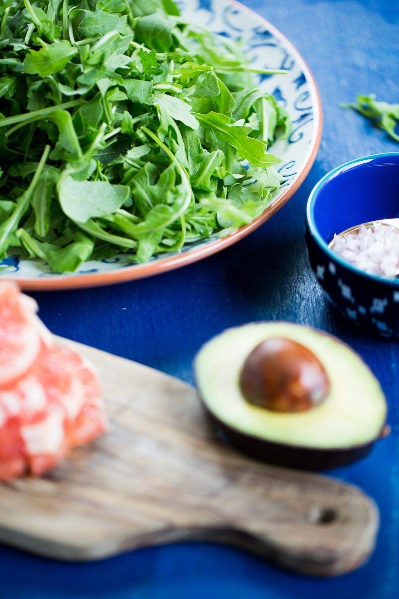 Platón con arugula, toronja, aguacate y un bol chico con aderezo.