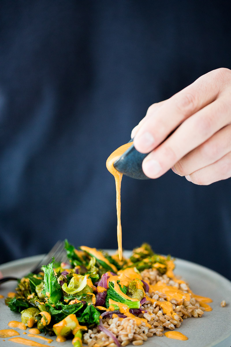Receta de verduras de invierno rostizadas con aderezo de pimiento rojo y granos ancestrales.