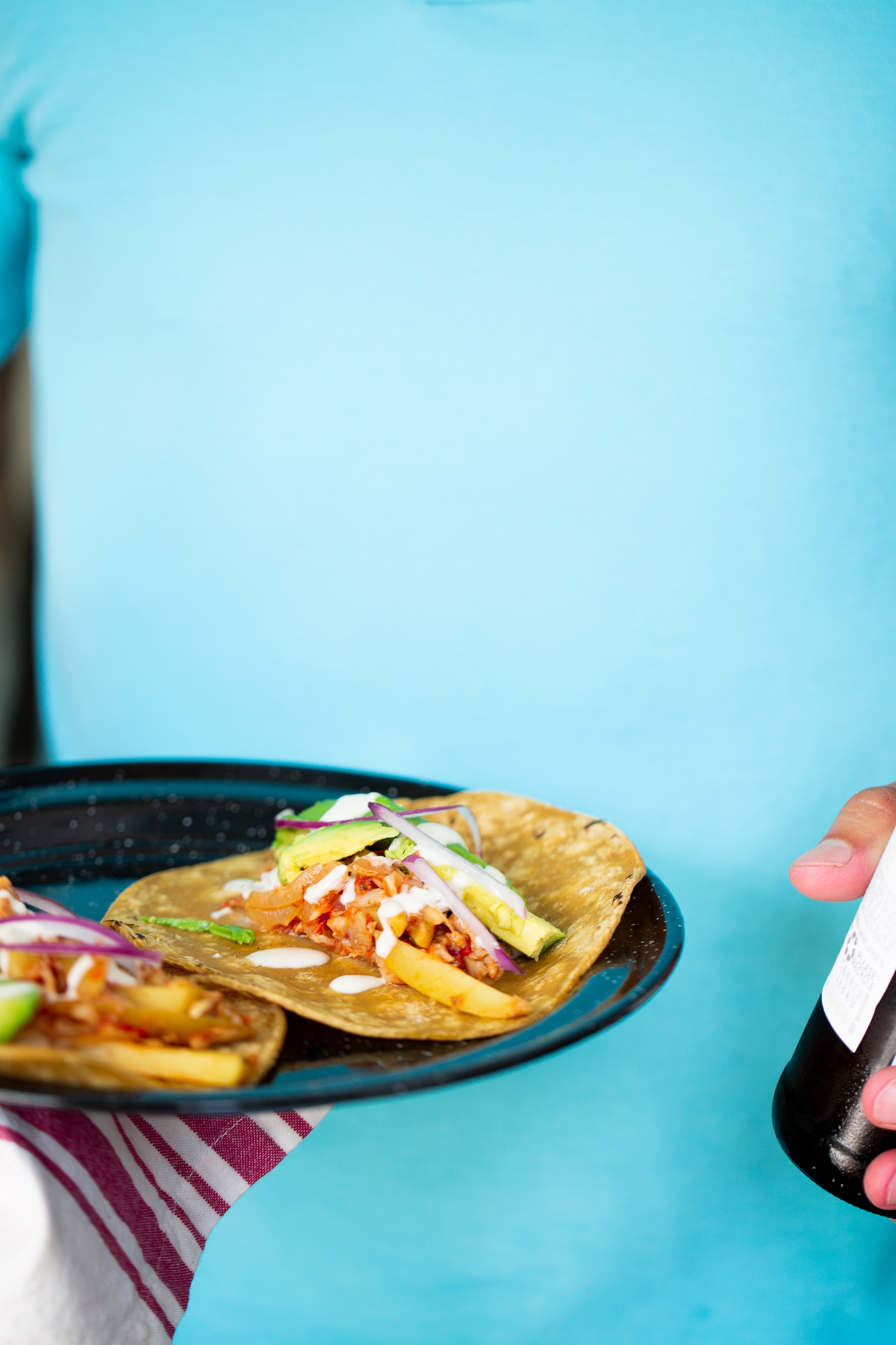 hombre deteniendo plato con tacos de tinga vegana 