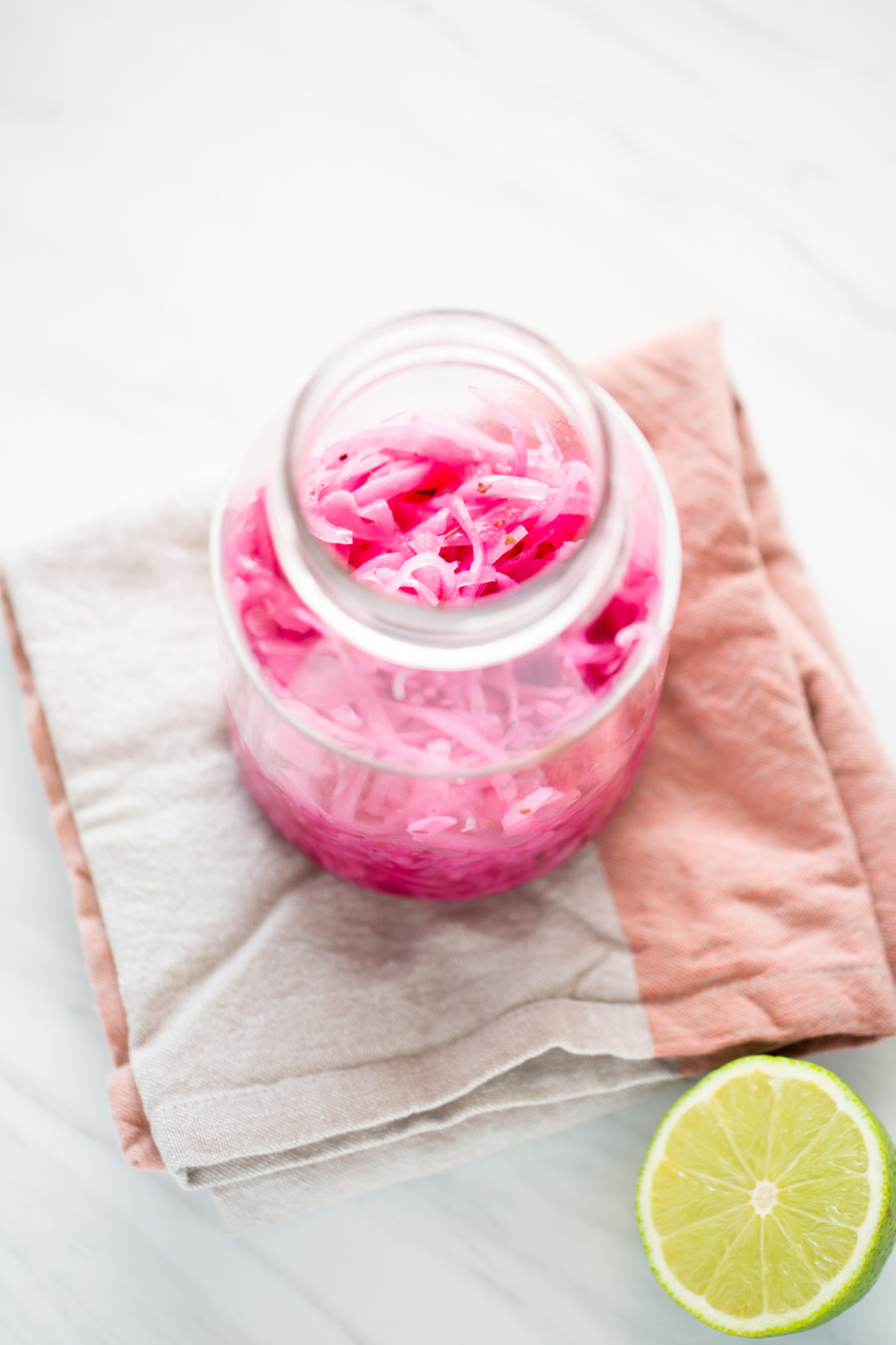 Frasco de vidrio con cebollas moradas encurtidas en vinagre con hierbas de olor, vistas de cerca