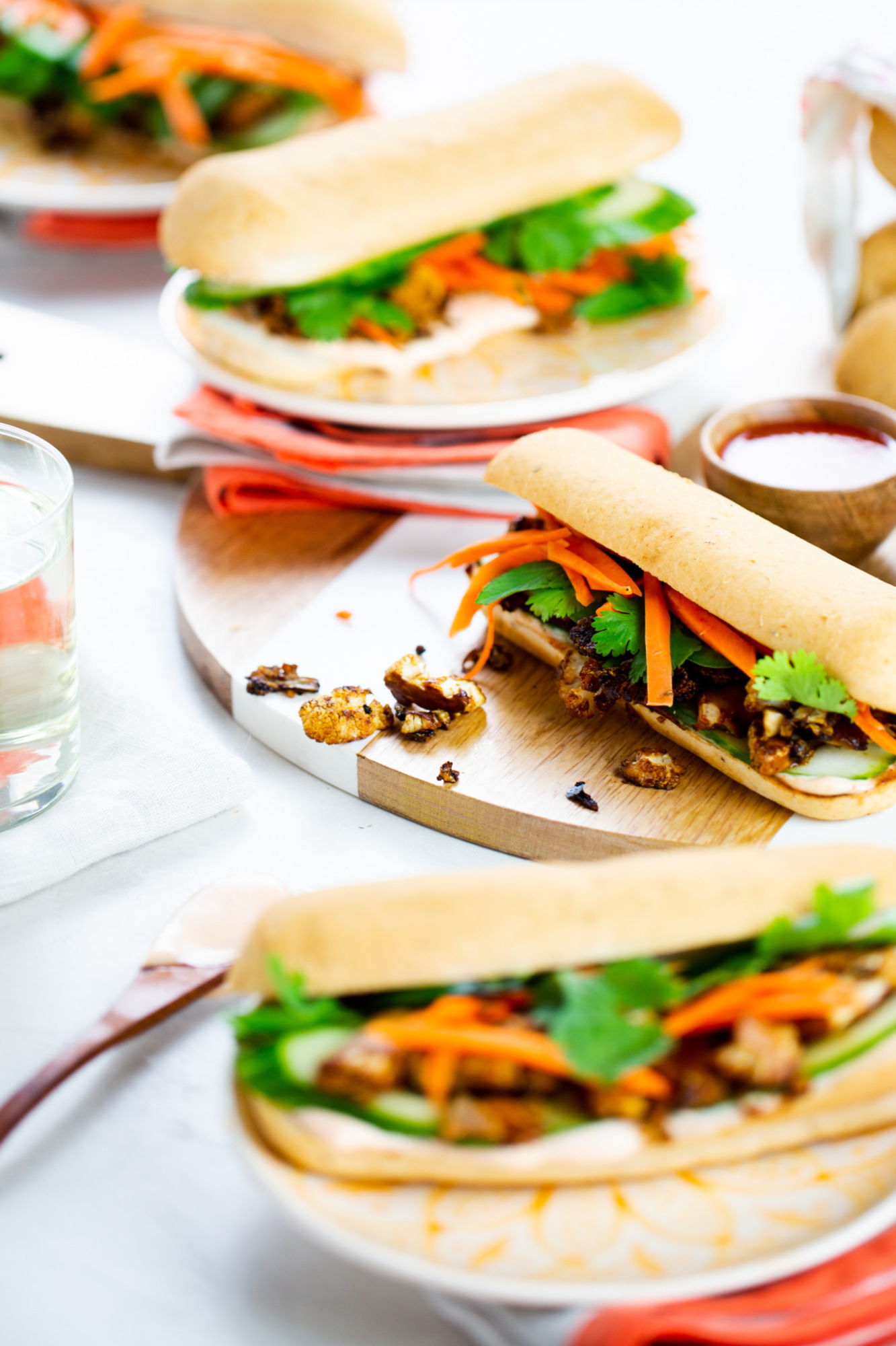  BANH-MI de coliflor en una tabla de madera con vasos de agua a un lado