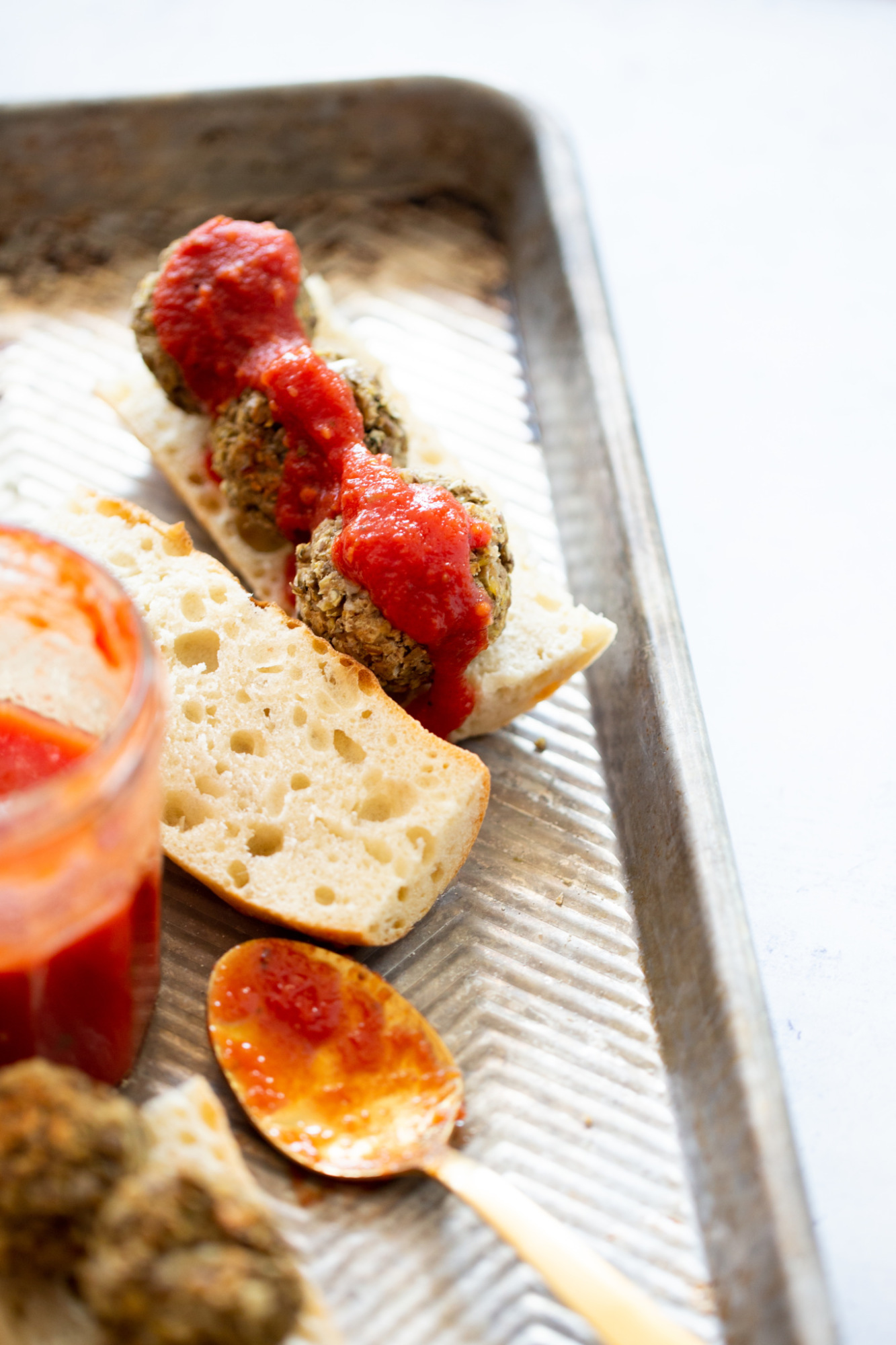 Sandwich de albondigas de lentejas abierto y bañado en salsa