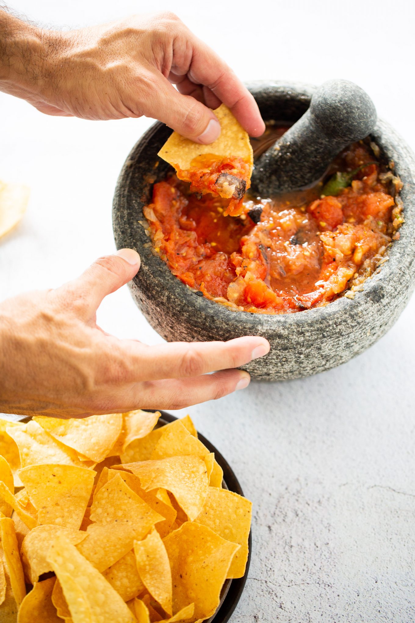 Molcajete con salsa roja y comiendola con totopos