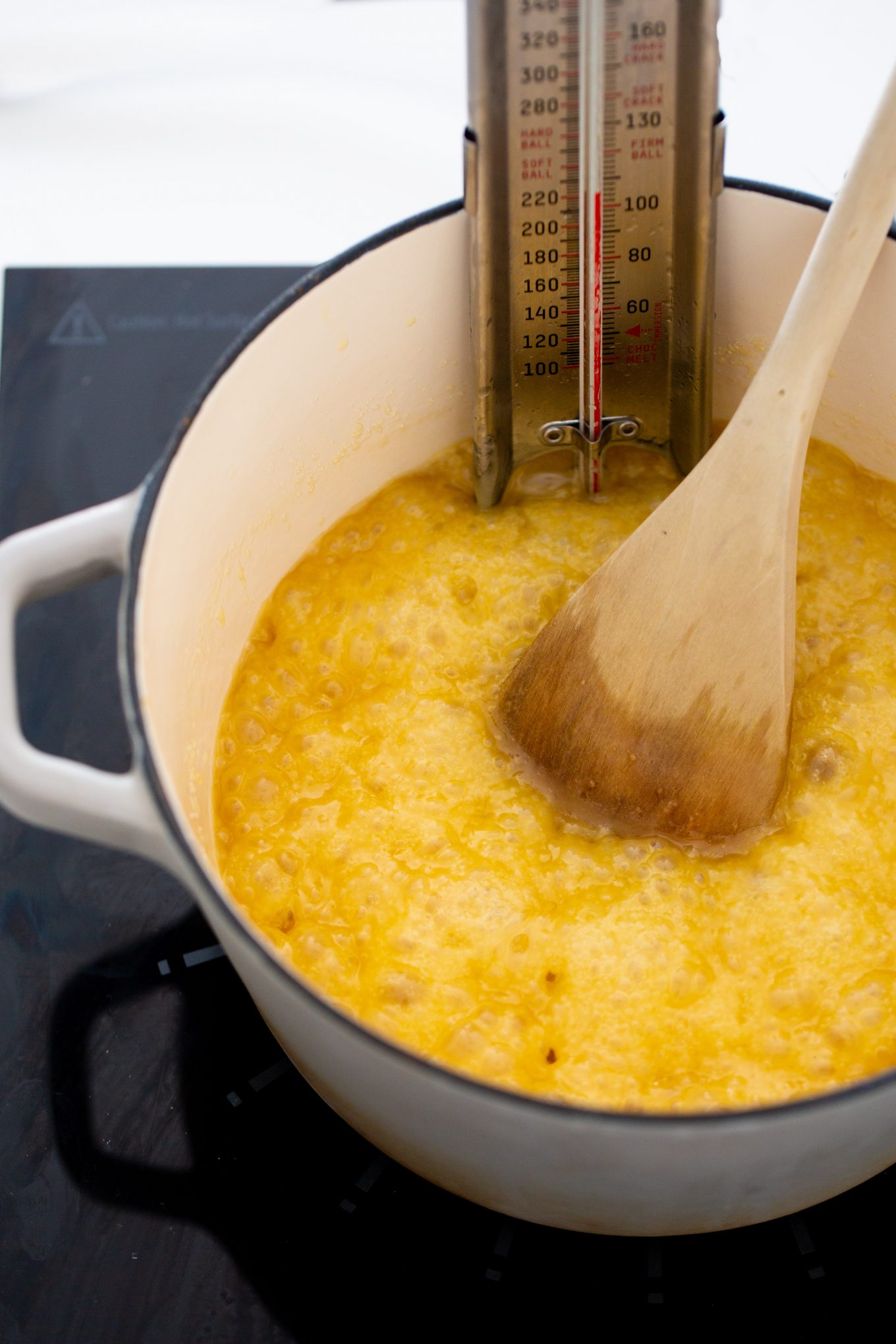 una olla con caramelo hirviendo y una pala de madera mociendolo