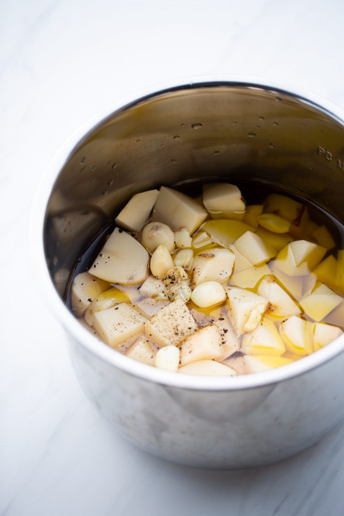 papas en trozos sin cocer en una olla con agua, ajo, aceite, sal