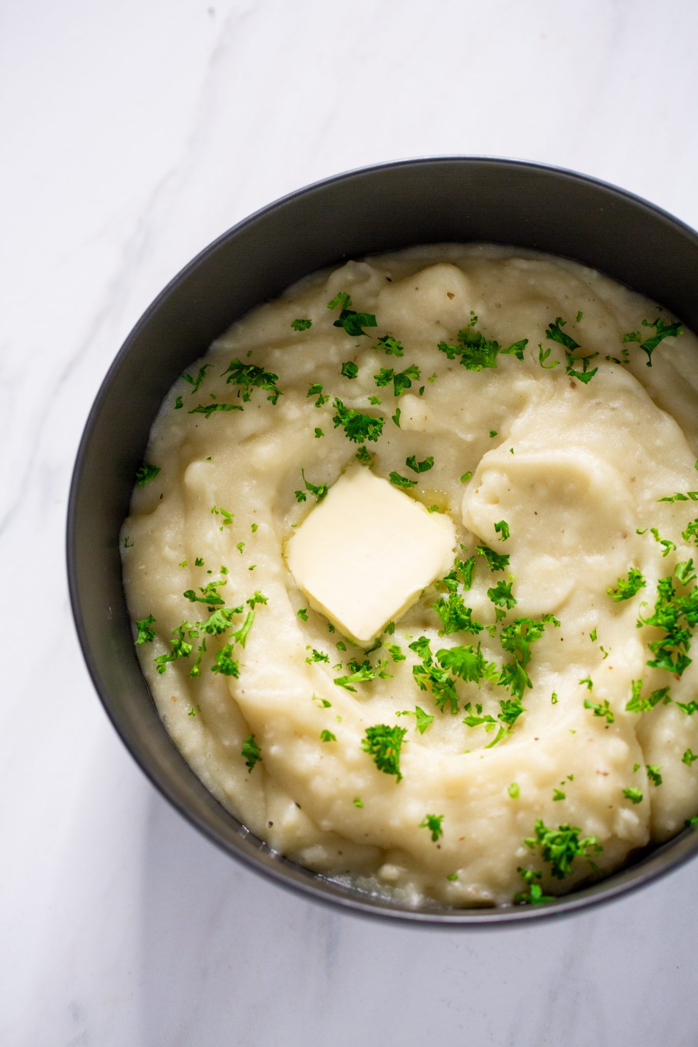 puré de papa en tazón negro con pedazo de mantequilla encima