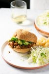 Un plato con un sándwich Sloppy Joe y una copa de vino.