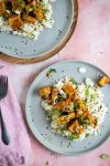 Un plato de arroz y tofu sobre fondo rosa, cubierto con tofu crujiente de naranja.