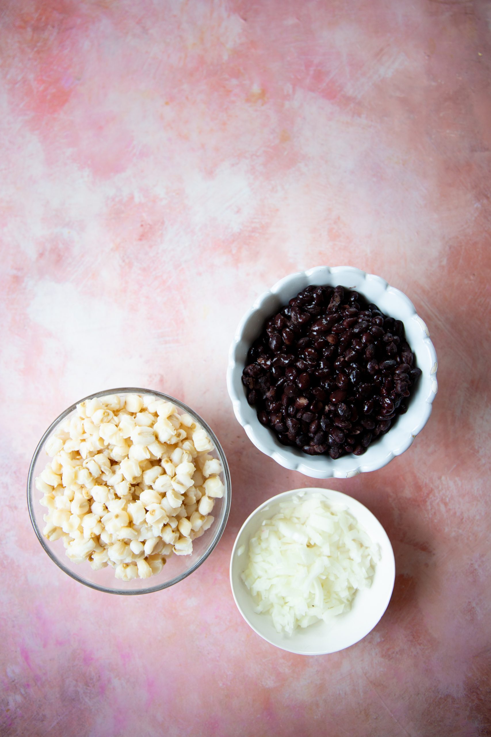 Tazones peque&ntilde;os con frijol negro, cebolla picada y ma&iacute;z pozolero blanco para preparar pozole