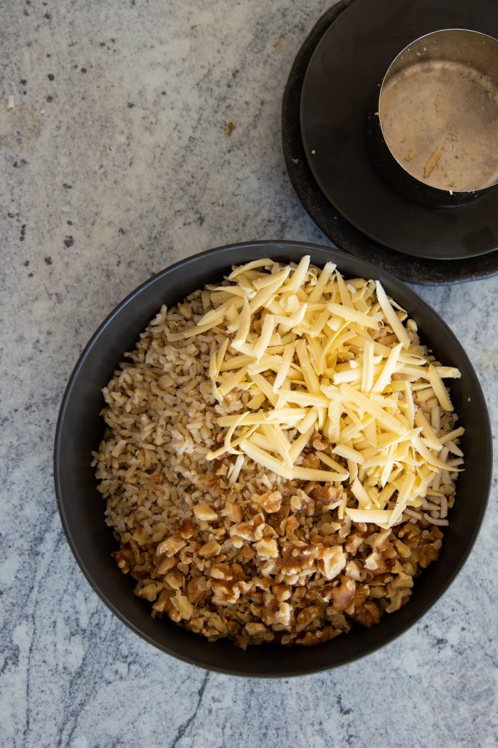 Tazón con uan mezcla de arroz integral, nuez picada y queso rallado.