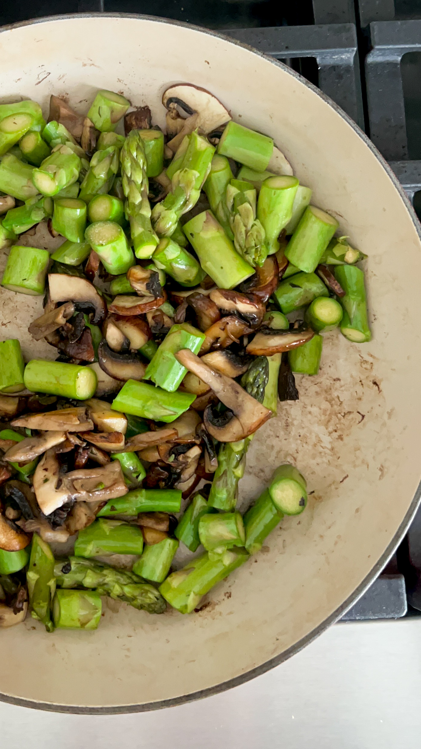 Esp&aacute;rragos y champi&ntilde;ones dor&aacute;ndose en un sart&eacute;n grande