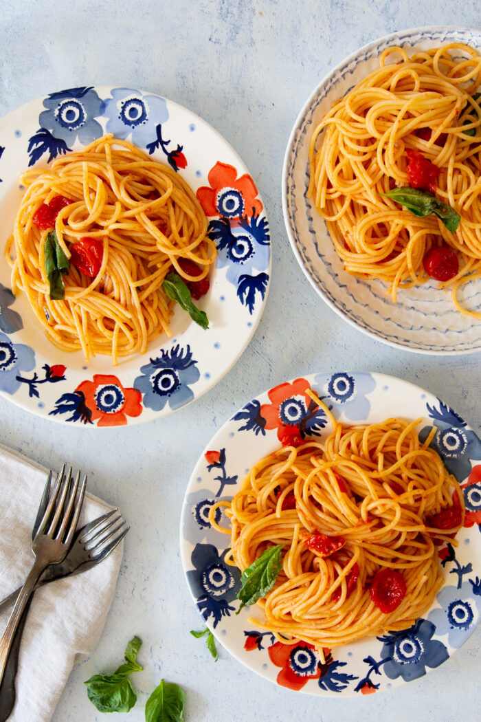 Tres platos con pasta con tomates cherry y albahaca