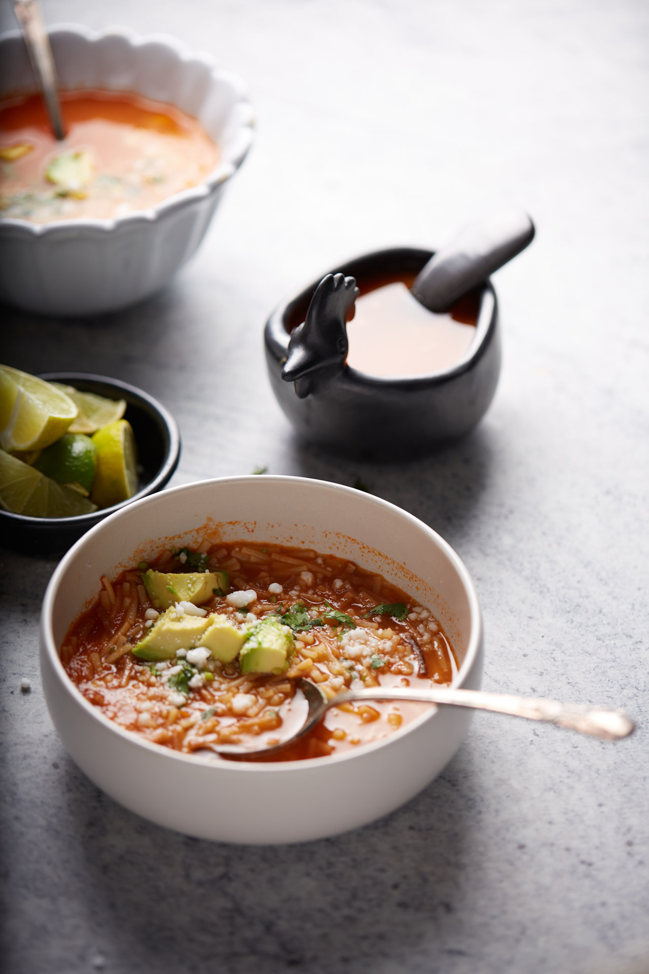 Plato de sopa de fideo con aguacate y lim&oacute;n.