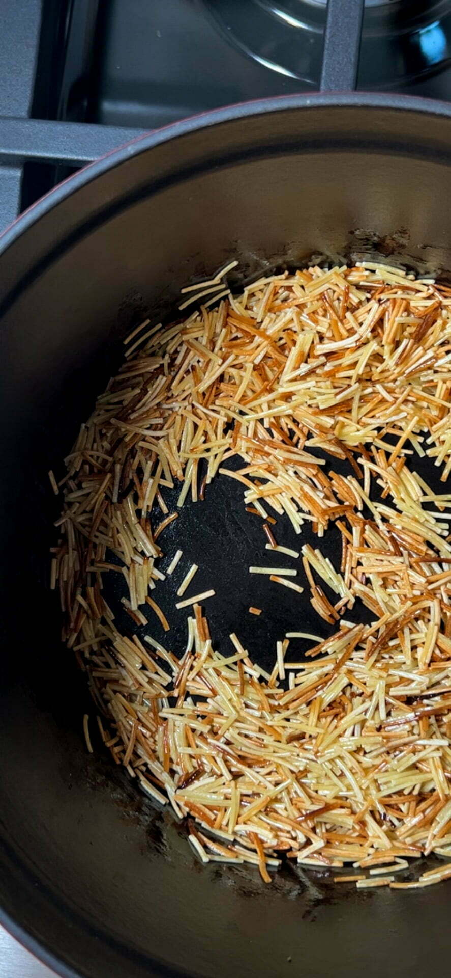 Fideos dorados en una olla con aceite.