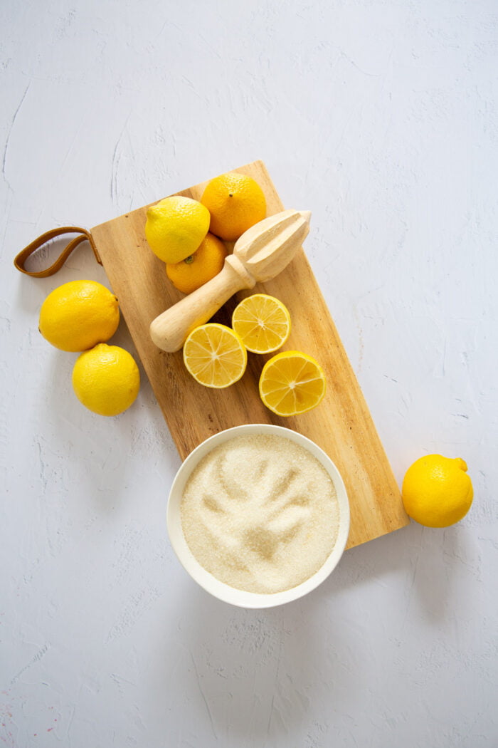 limones amarillos partidos a la mitada sobre una tabla y azucar en un tazon