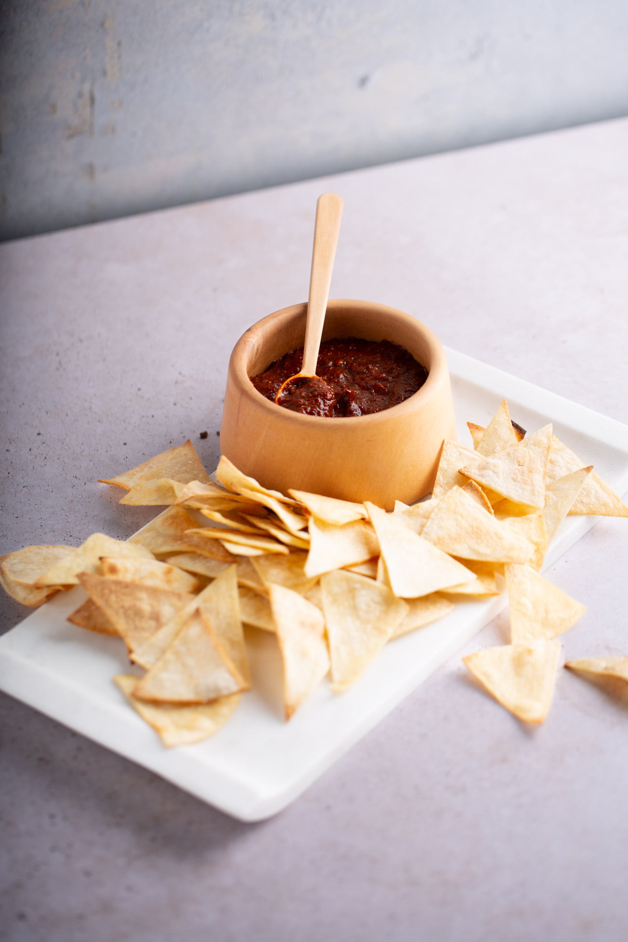 Salsa Tlaquepaque servida en un salsero de madera con totopos de maiz alrededor
