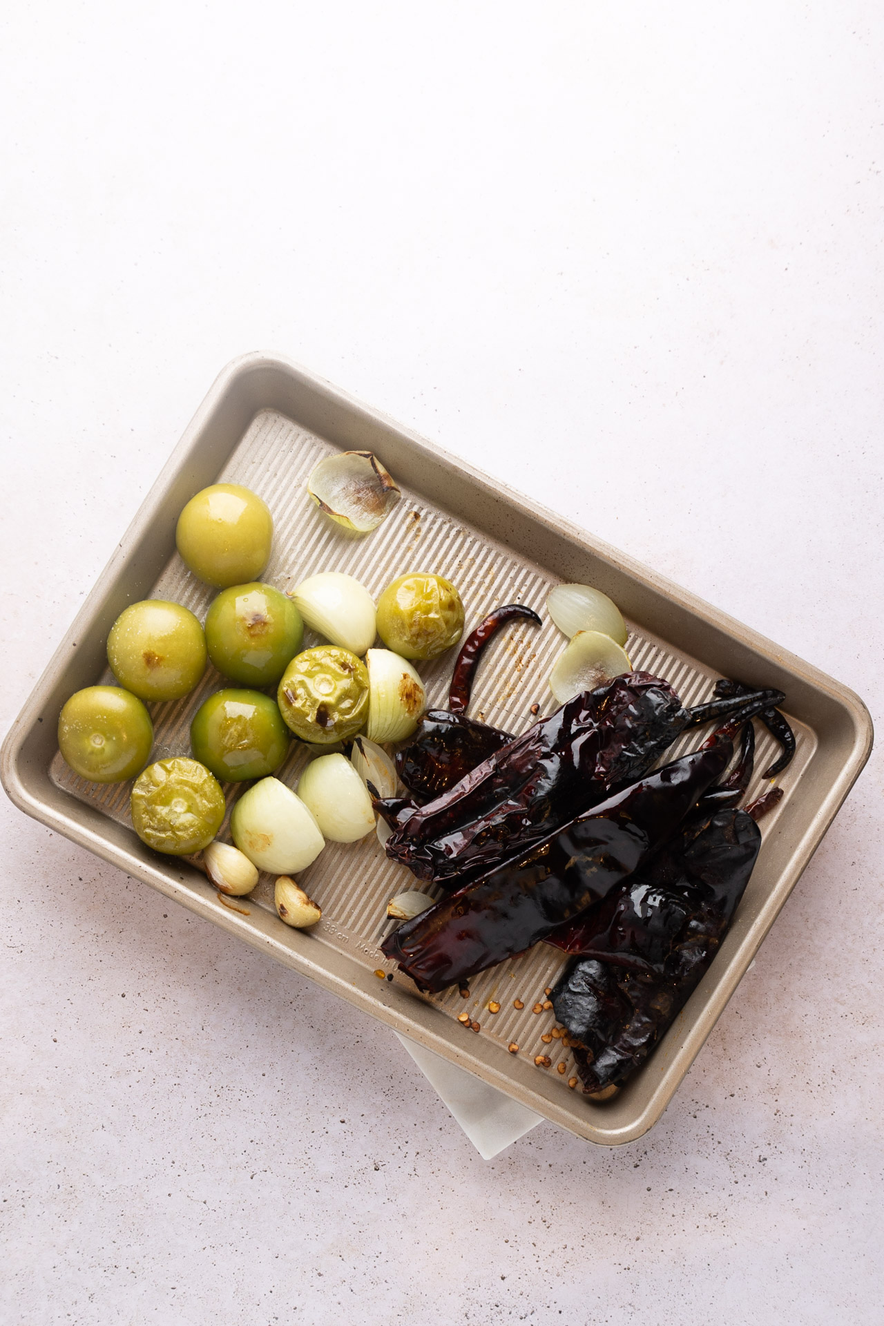 tomatillos, ajo, cebolla y chiles asados sobre una charola de horno