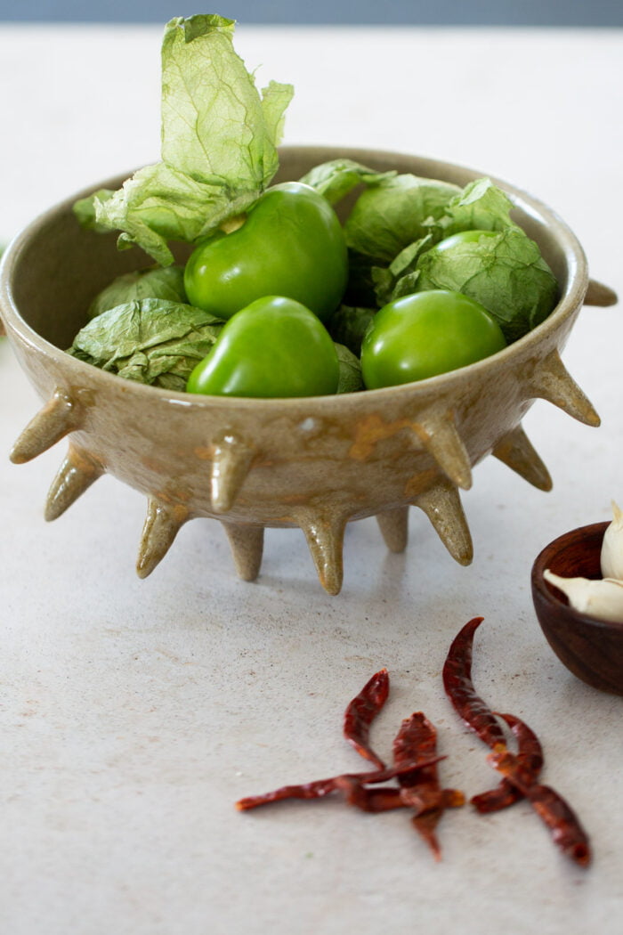 Tomatillos en un platón y chiles de arbol a un lado