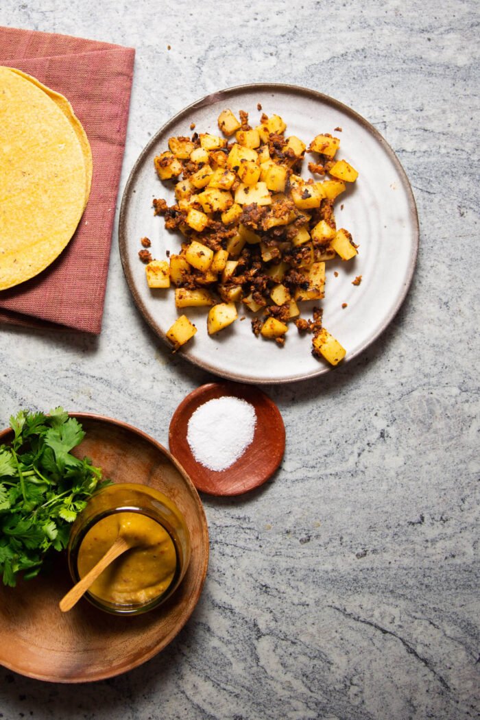 papas con chorizo en un plato anidado a tortillas de maíz, cilantro fresco y un mini tazón de salsa