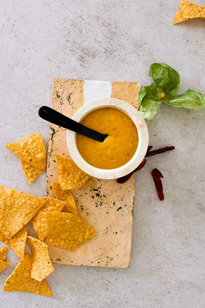 salsa de chile de arbol en un platito con papas fritas y cáscara de tomatillos a un lado