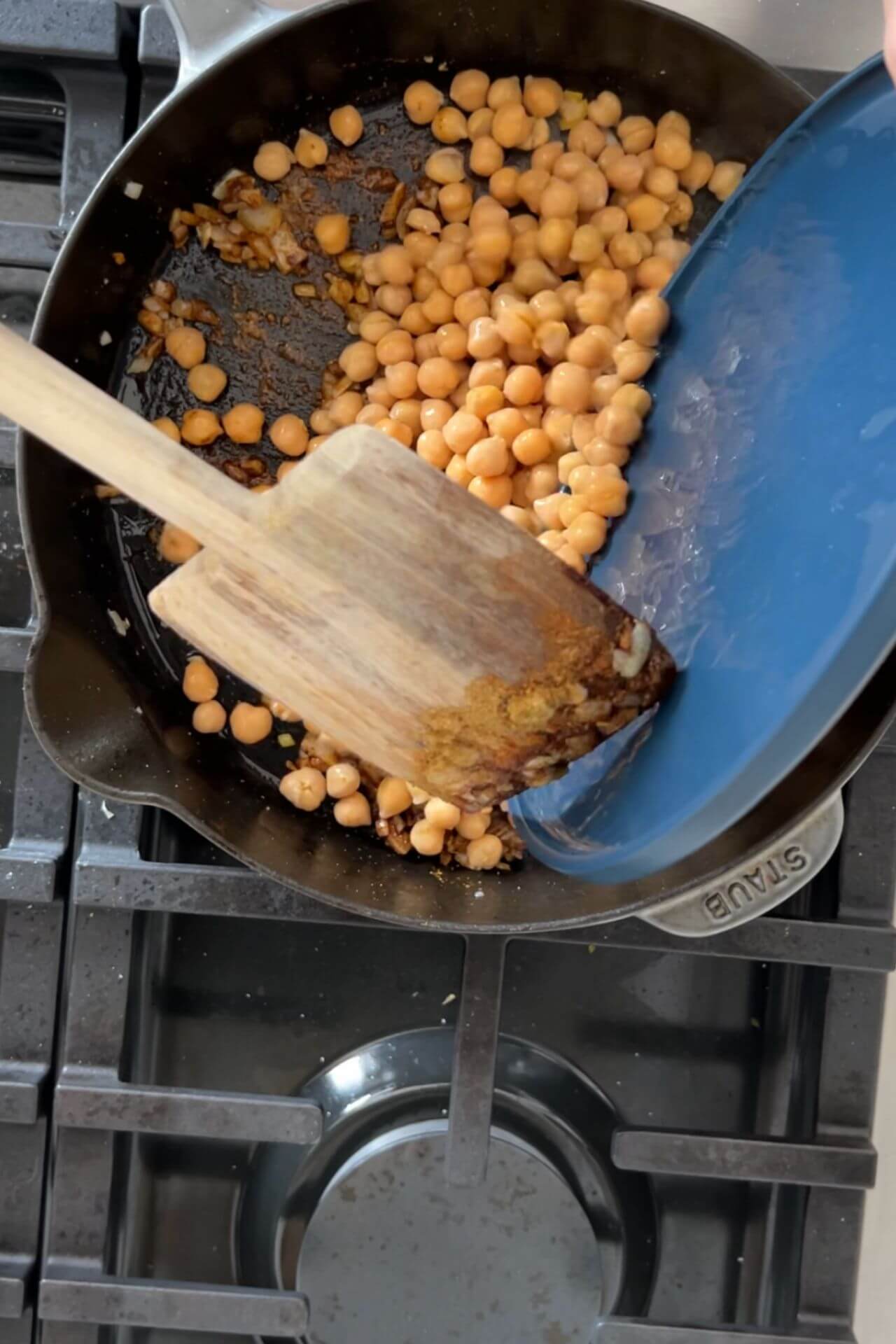 Poninedo garbanzos en un sartén.