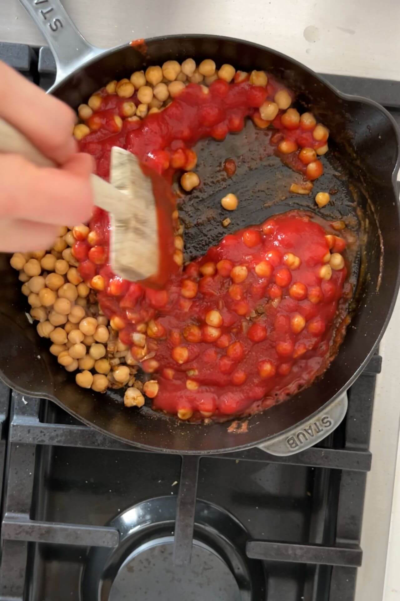 Un sartén de hierro forjado con garbanzos y salsa de tomate.