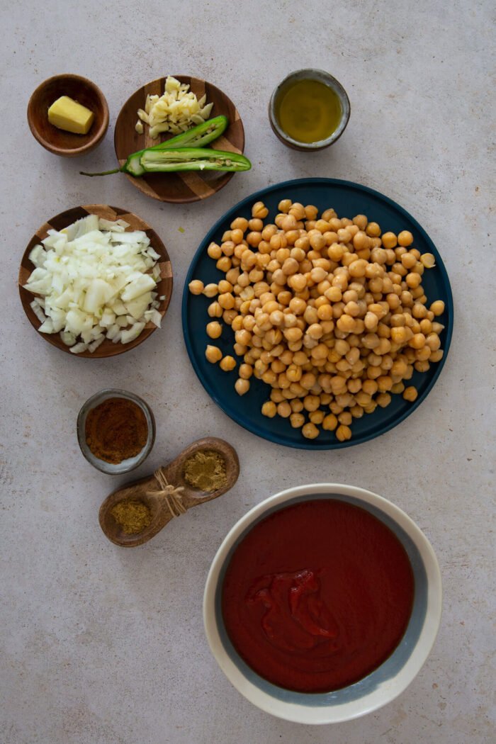 garbanzos, cebolla picada, chile y ajo, un pedazo de jengibre, pure de tomate y especias en mise en place listas para usarse.