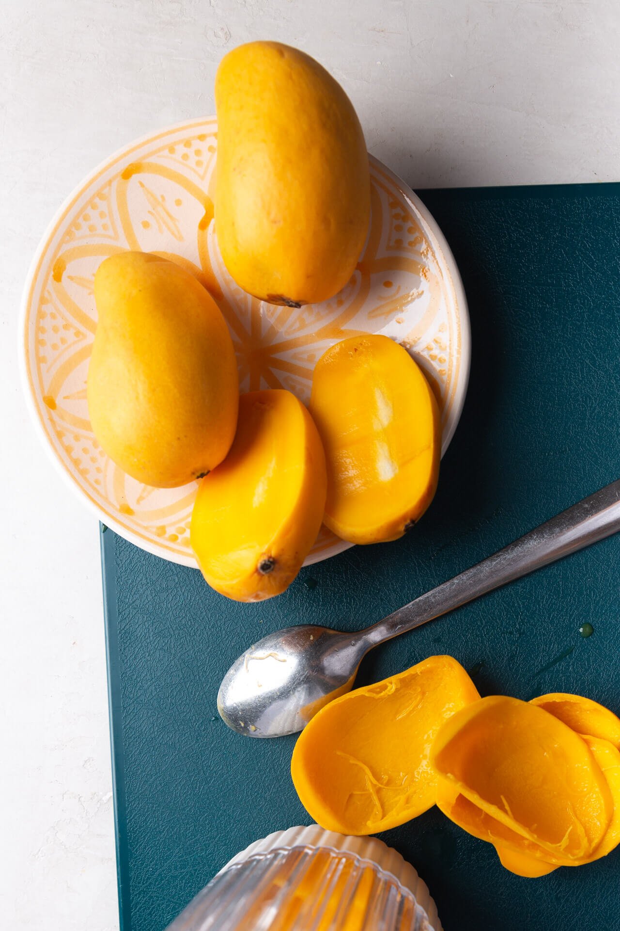 mangos cortados por la mitad sobre una tabla de cortar verde