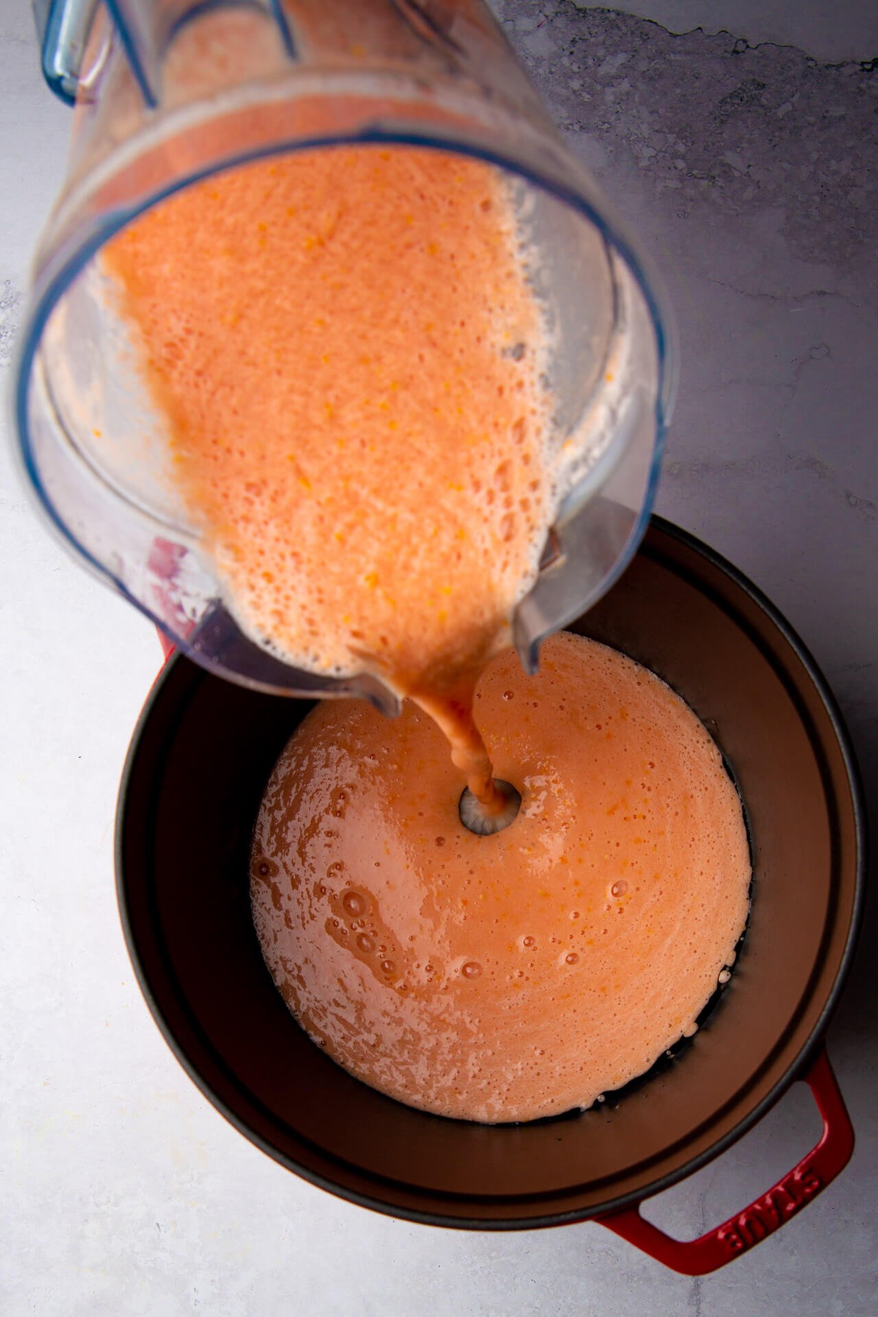 vaciando caldo de tomate a una olla de hierro forjado