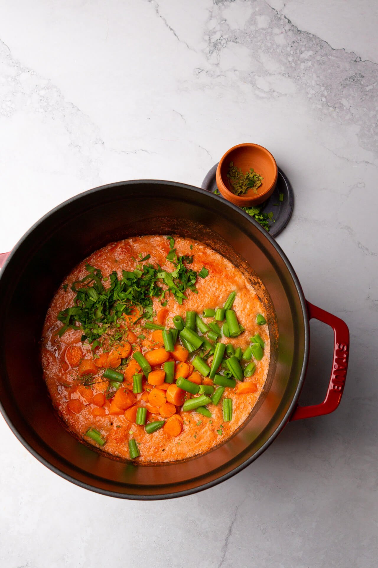 olla de hierro forjado con caldillo, ejotes, zanahorias y hierbas de olor