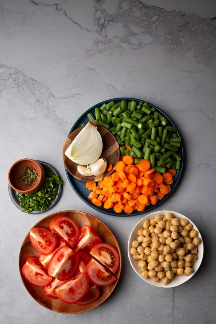 tomates rebanados, garbanzos cocidos, ejotes y zanahorias en trozos, cebolla y ajo. Ingredientes para hacer caldo tlalpeño sin pollo.