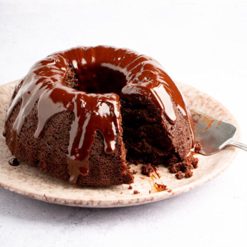 Un bundt cake de chocolate en un plato con un trozo sacado.