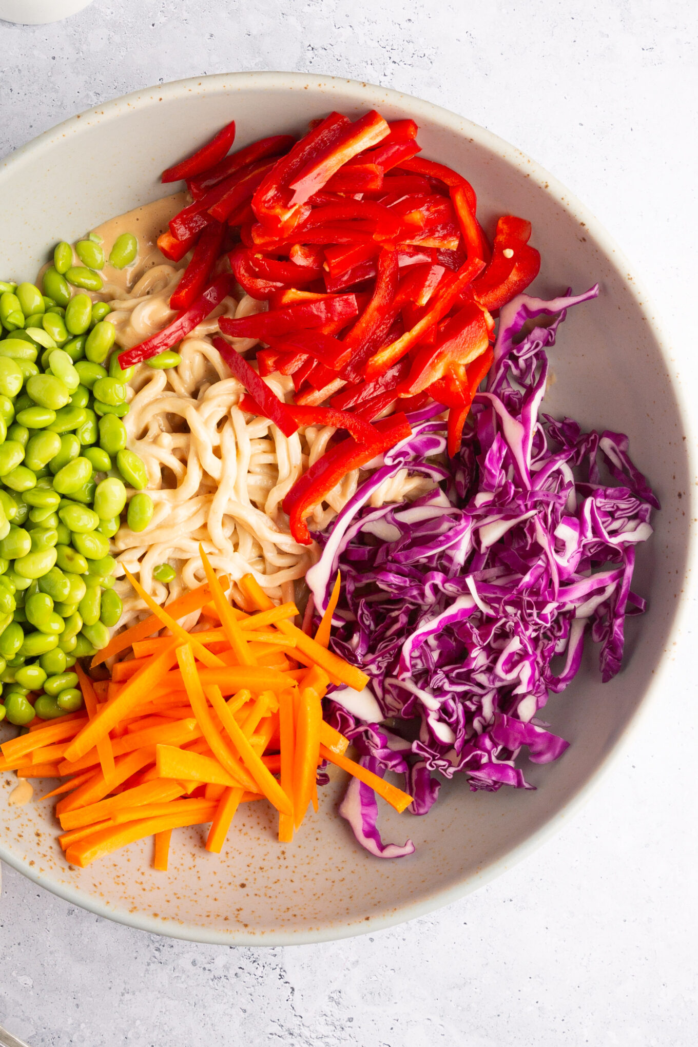 tazón grande con fideos, con aderezo cremoso y cabagge rojo, edamame, pimiento rojo y zanahorias