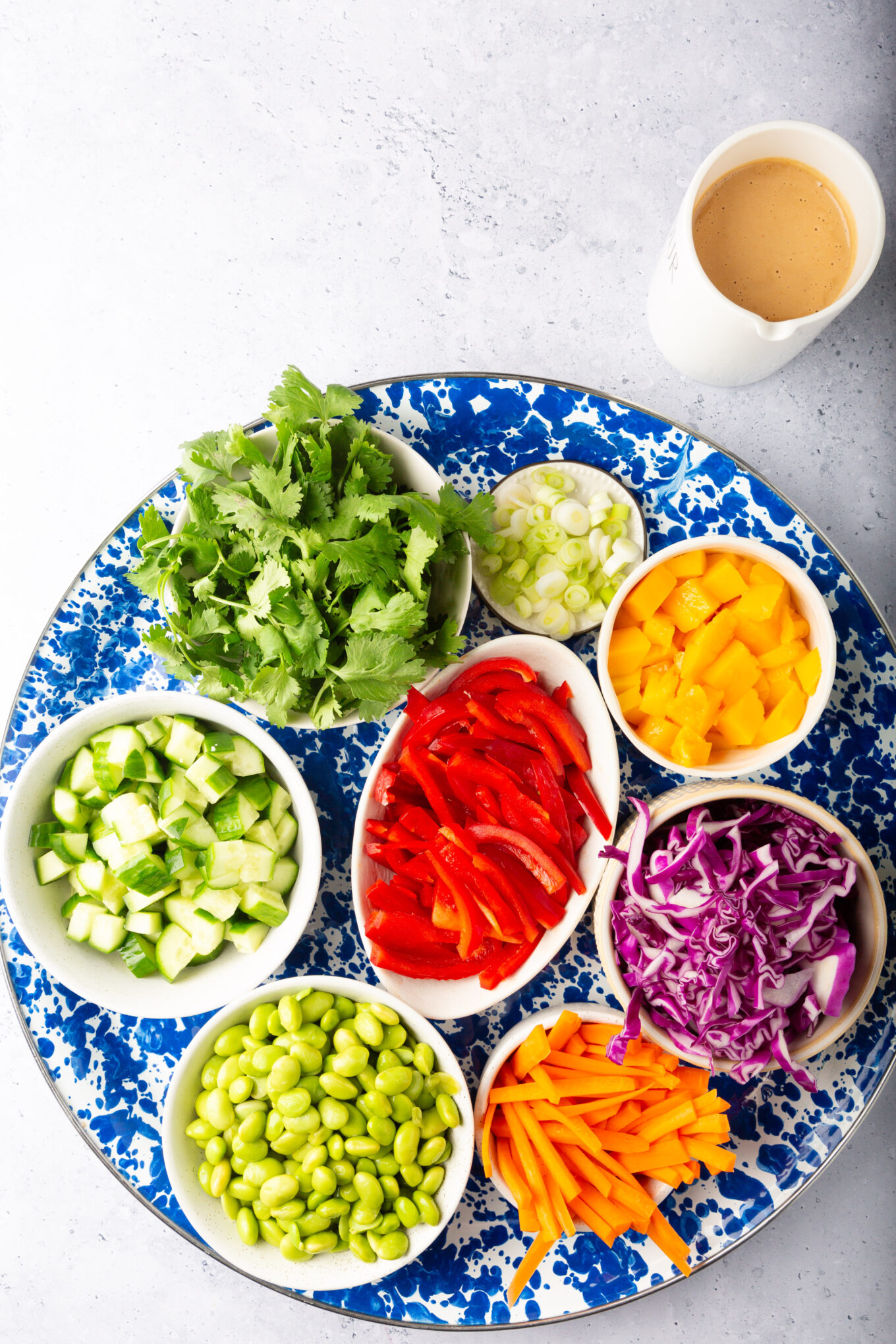 Hay varios tipos de verduras visibles. Esto incluye lo que parecen ser pimientos rojos cortados en rodajas finas, col morada rallada y posiblemente algunas verduras de hoja verde.