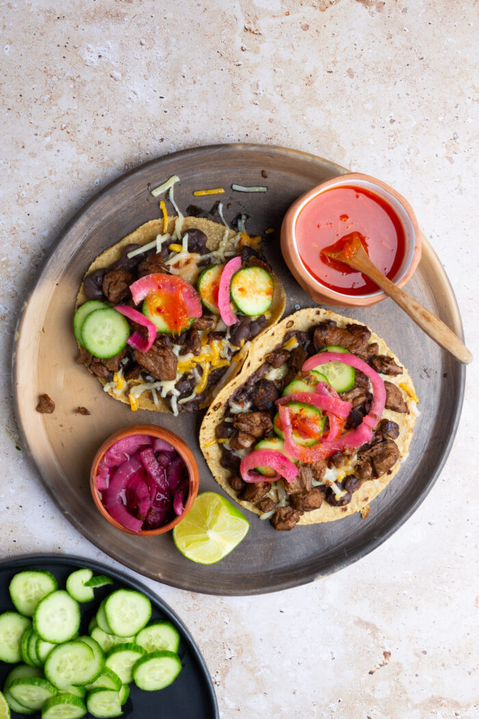 Plato de barro con dos lorenzas veganas, un plato de salsa a un lado, limones y cebollas en vinagre mexicanas