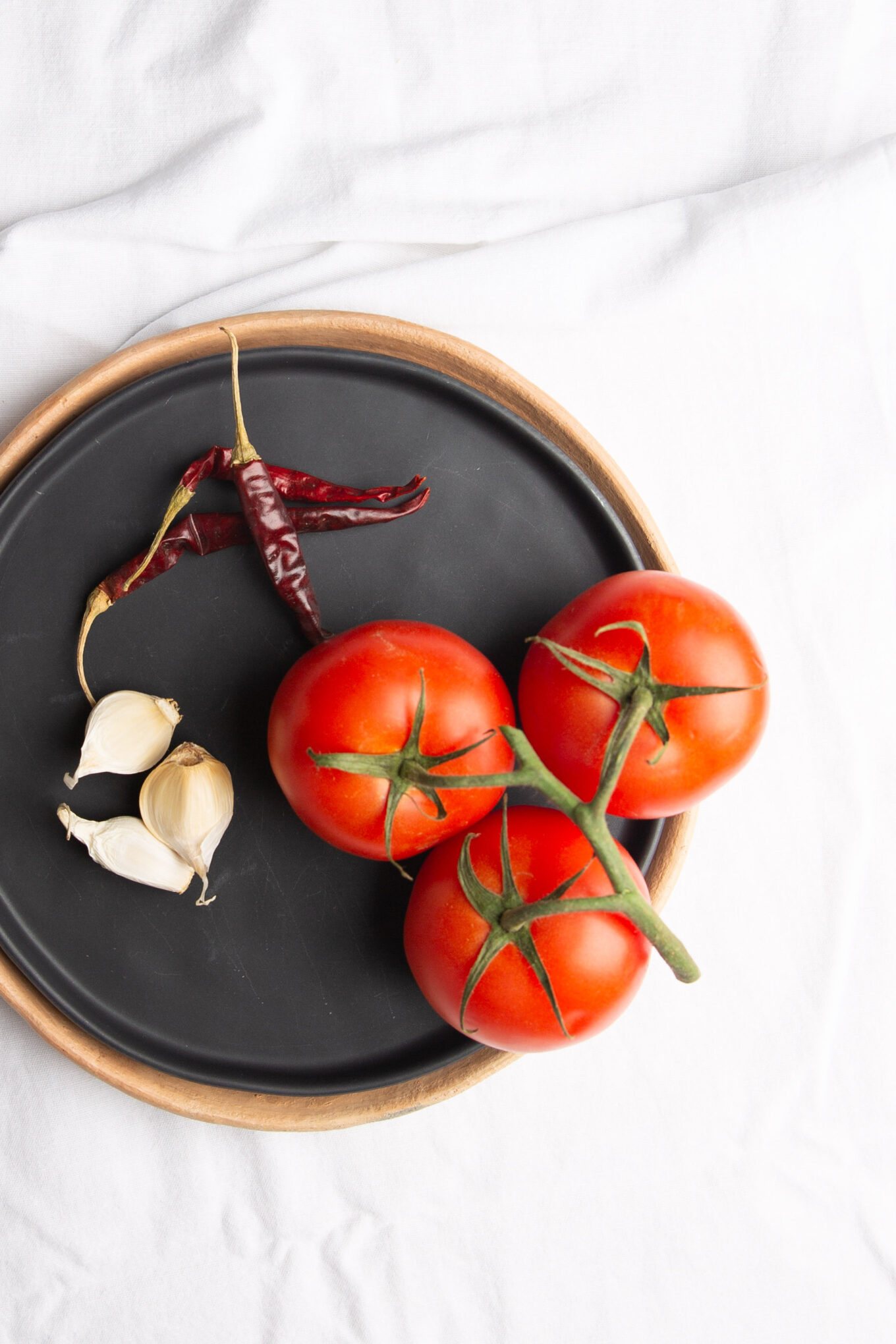Un plato negro con tomates, ajo y chiles - Estrujadas Veracruzanas.