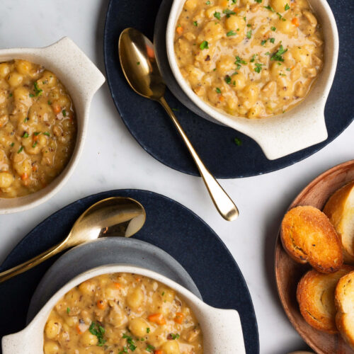 Tres cuencos de sopa de ñoquis de salchicha deliciosamente cremosa y pan en una mesa.