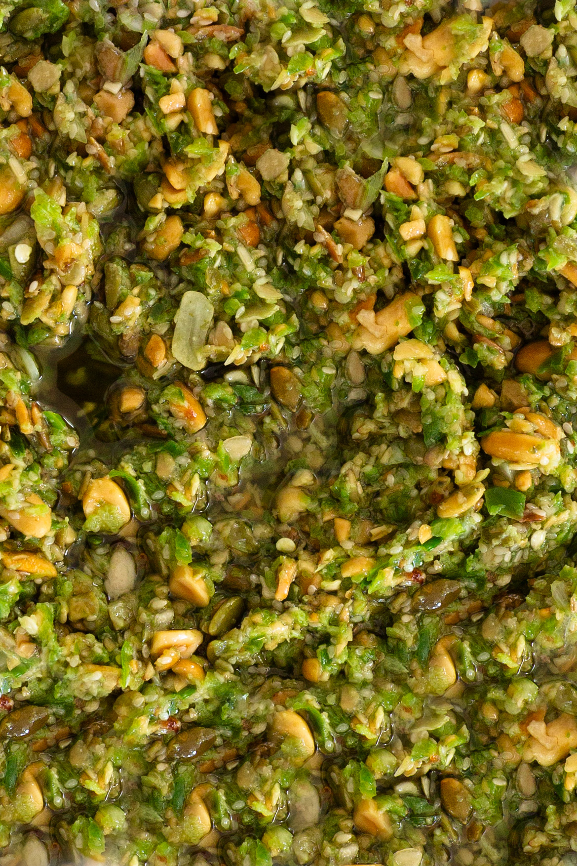 Primer plano de un cuenco de pesto verde con pipas de calabaza.