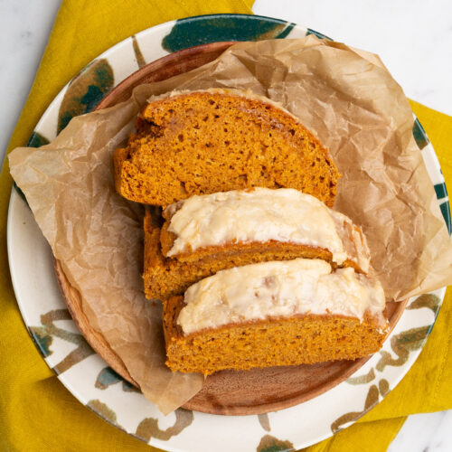 Una rebanada de pan de calabaza vegano espolvoreada con especias, servida en un plato.