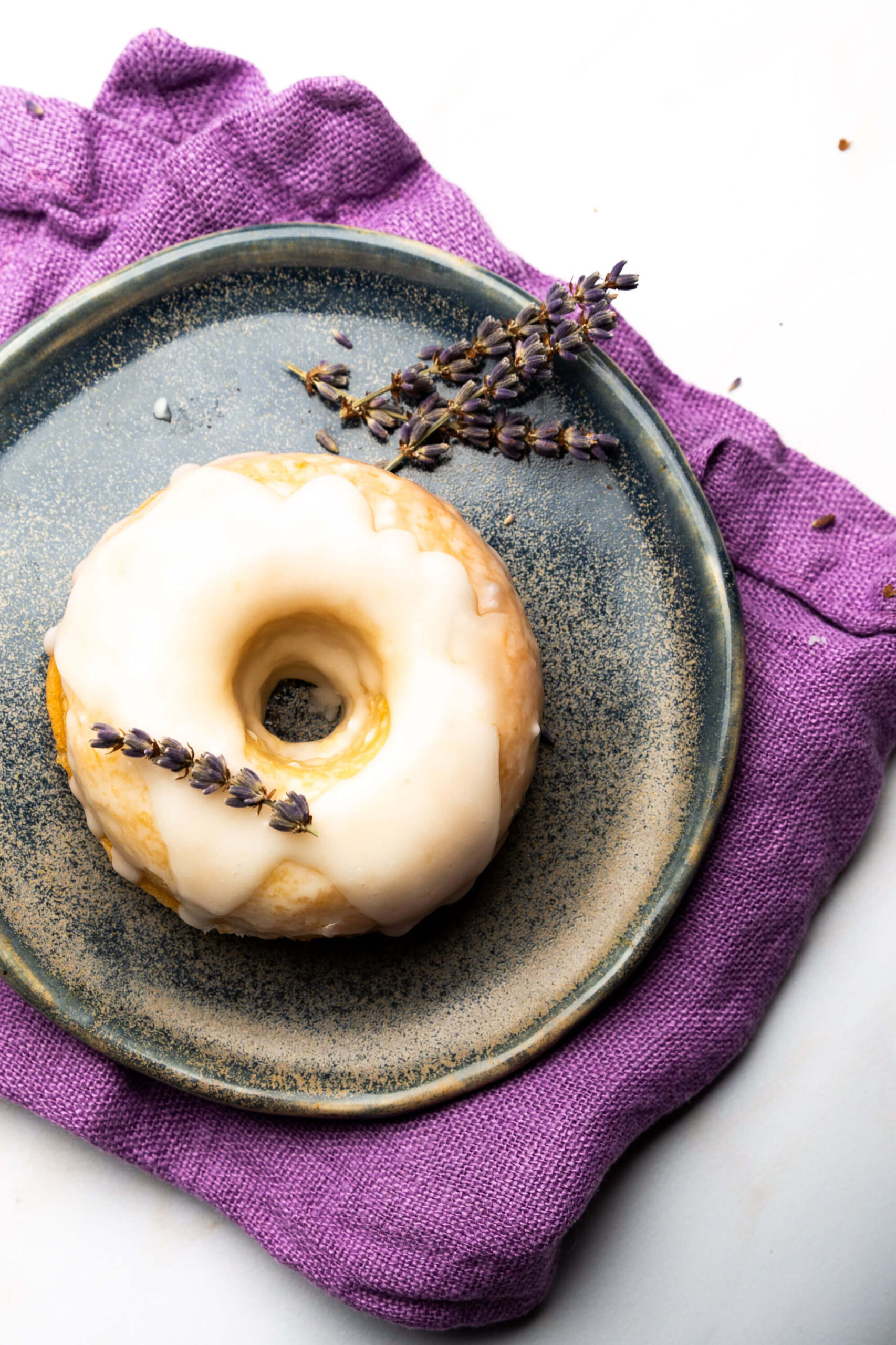 Un donut vegano con glaseado de lavanda en un plato.