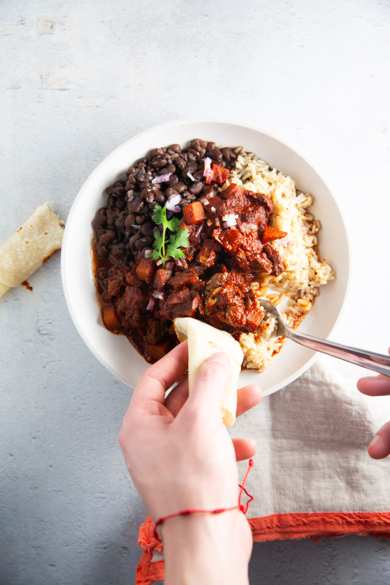 Una persona comiendo un plato de frijoles negros y arroz.