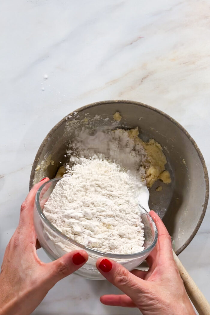 A person preparing day of the dead cookies, pouring flour into a bowl.