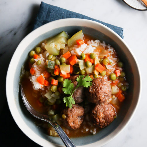 Un plato de sopa vegana con albóndigas y verduras.
