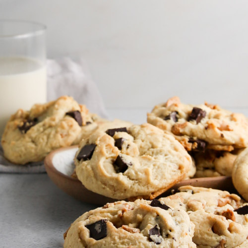 Galletas con chispas de chocolate en un plato junto a un vaso de leche.