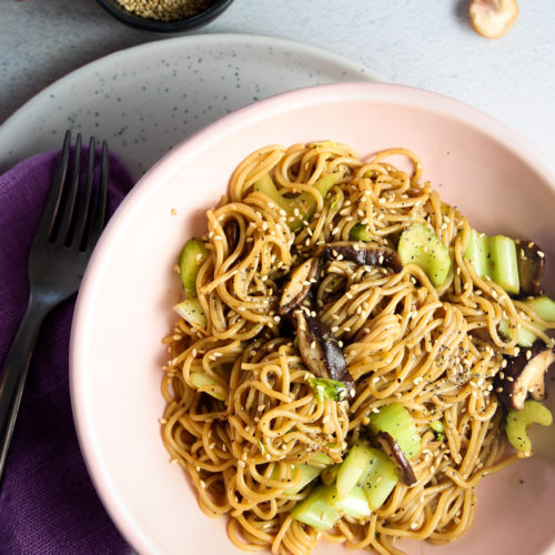 Un cuenco de fideos con champiñones y pimienta negra espolvoreados con semillas de sésamo.