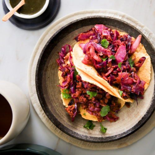 Tacos de col roja en un plato con una taza de café.